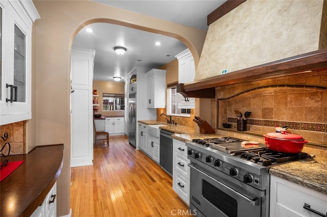 kitchen with white cabinets, tasteful backsplash, appliances with stainless steel finishes, light hardwood / wood-style floors, and sink