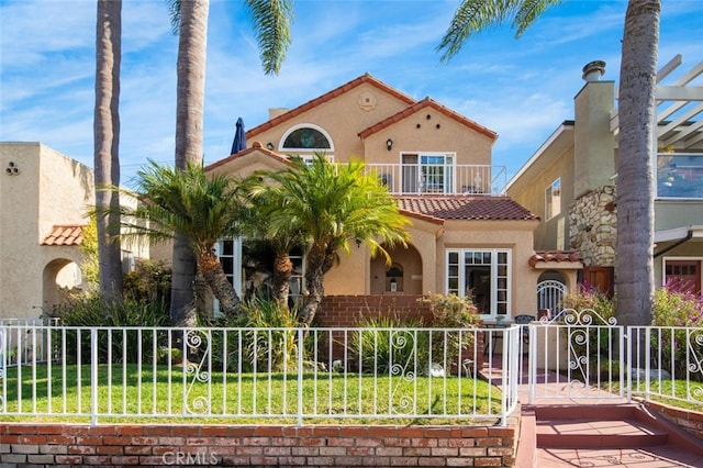 mediterranean / spanish house with a balcony and a front lawn