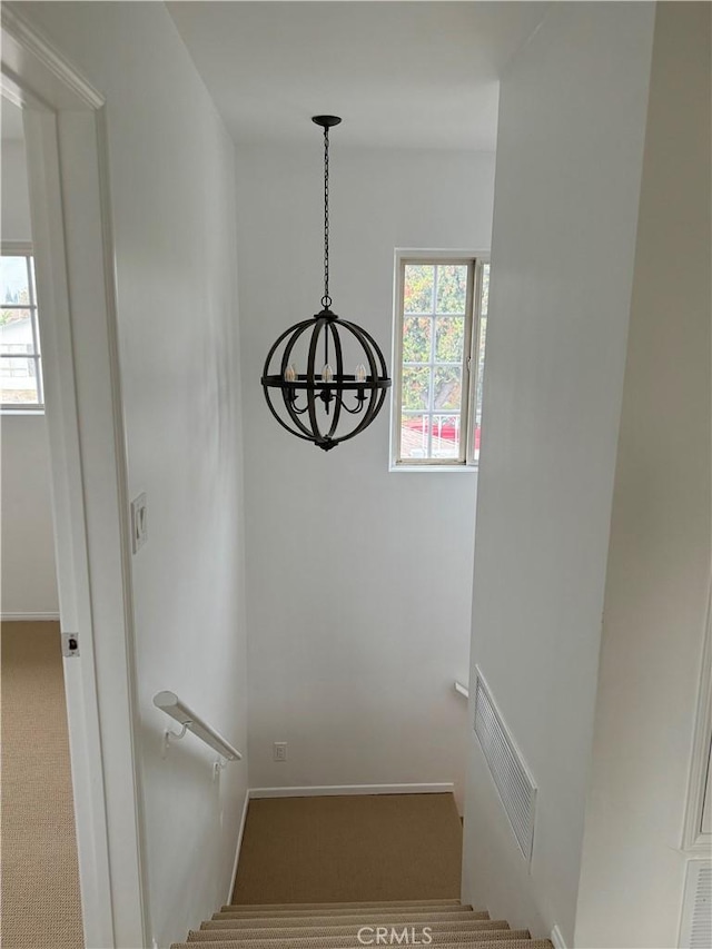 stairway with carpet and a notable chandelier