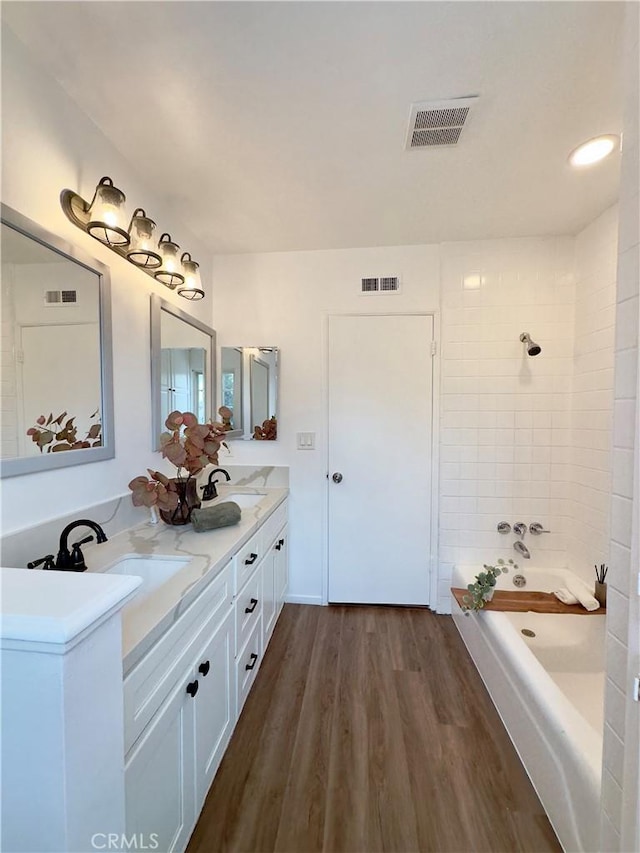 bathroom with vanity, wood-type flooring, and tiled shower / bath combo