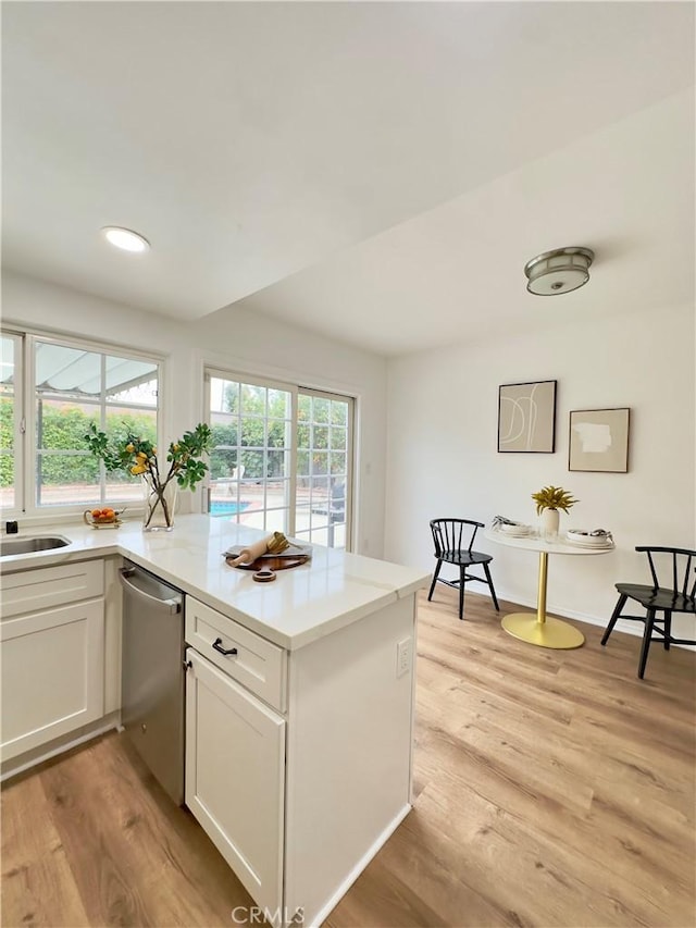 kitchen with stainless steel dishwasher, light hardwood / wood-style floors, white cabinetry, and kitchen peninsula