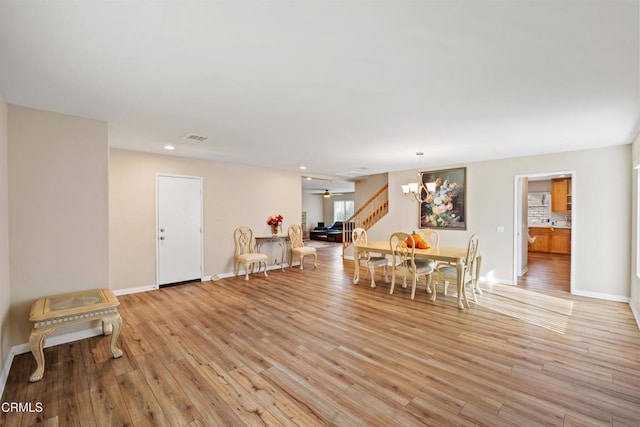 dining area featuring ceiling fan with notable chandelier and light hardwood / wood-style flooring