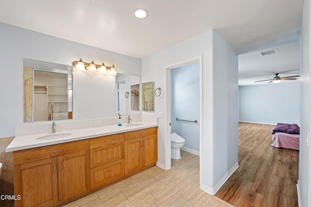 bathroom with vanity, hardwood / wood-style flooring, toilet, and ceiling fan