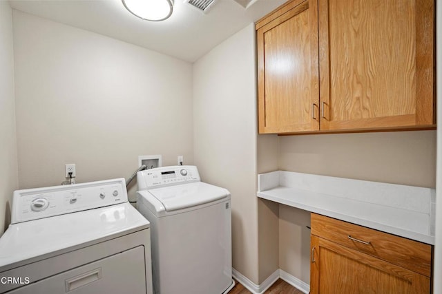 washroom featuring washer and clothes dryer, cabinets, and wood-type flooring