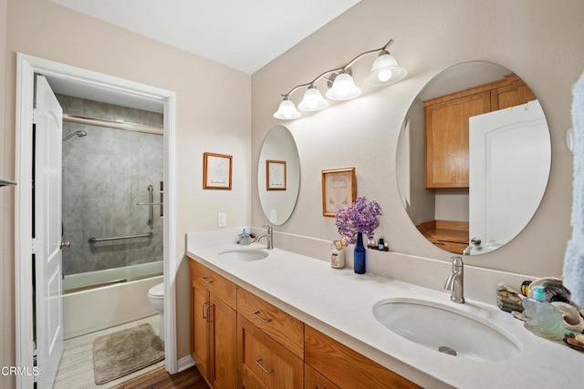 full bathroom with hardwood / wood-style floors, vanity, toilet, and bath / shower combo with glass door