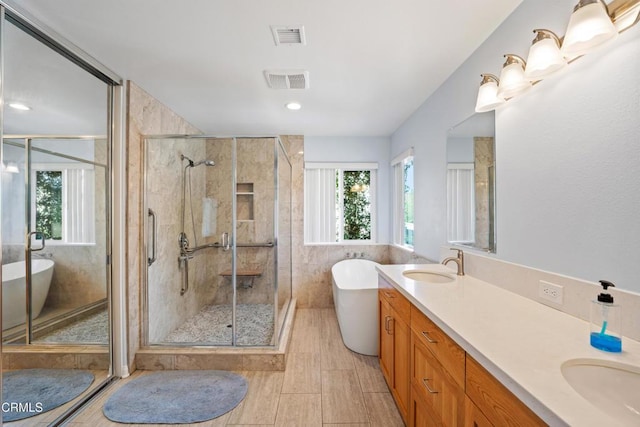 bathroom with a stall shower, plenty of natural light, a soaking tub, and a sink