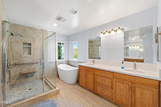 full bath featuring a freestanding tub, a sink, and visible vents