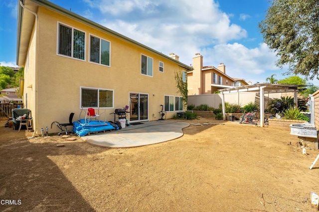 rear view of house featuring a patio area, stucco siding, fence, and a pergola