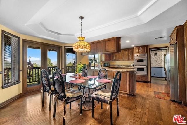 dining space featuring a tray ceiling, sink, french doors, and dark hardwood / wood-style floors