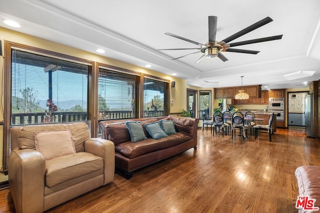 living room with a raised ceiling, a wealth of natural light, ceiling fan, and hardwood / wood-style flooring