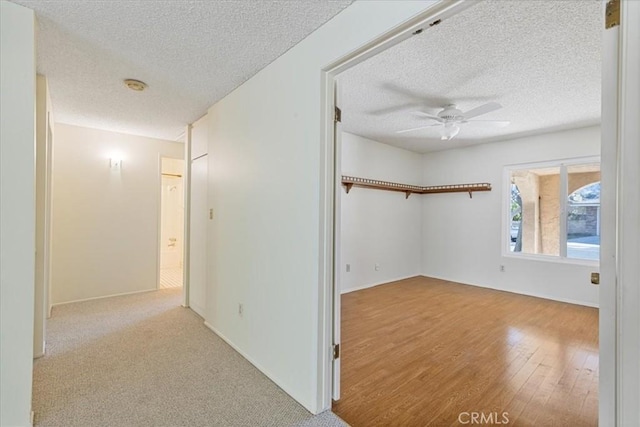 hall featuring a textured ceiling and light hardwood / wood-style flooring