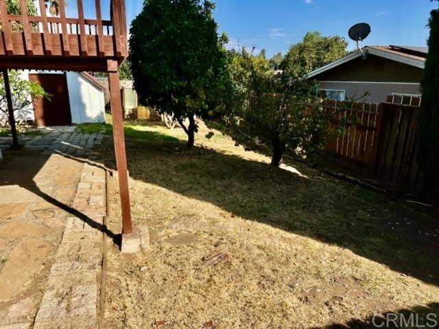 view of yard with a deck, a storage unit, and a patio area