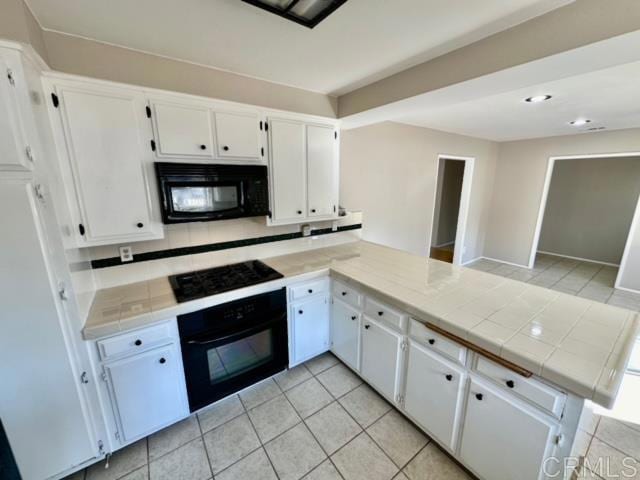 kitchen with tile countertops, black appliances, white cabinets, decorative backsplash, and kitchen peninsula