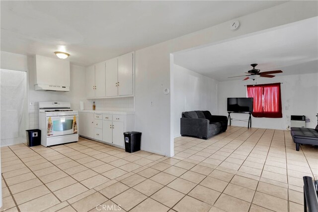 10394 Baker Rd, Lucerne Valley, CA 92356 - kitchen with white cabinets, ceiling fan, white stove, light tile patterned flooring, and ventilation hood