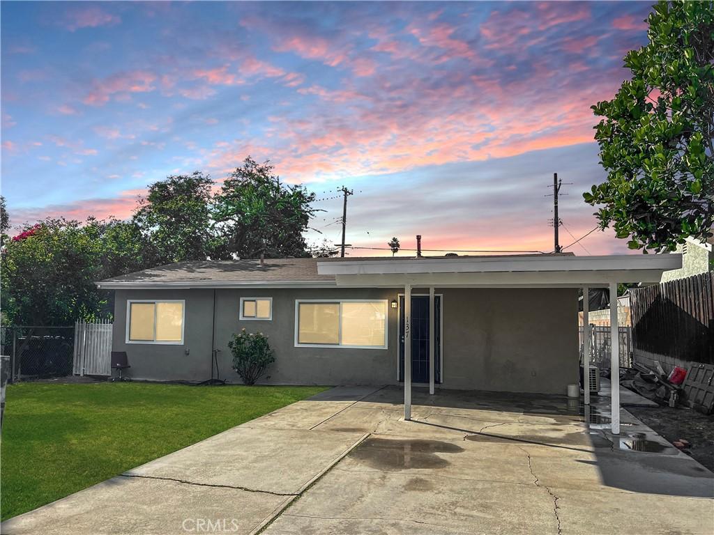 back house at dusk featuring a yard and a carport