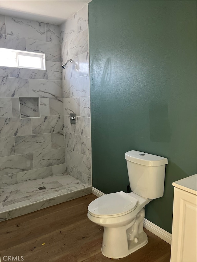 bathroom with tiled shower, wood-type flooring, and toilet