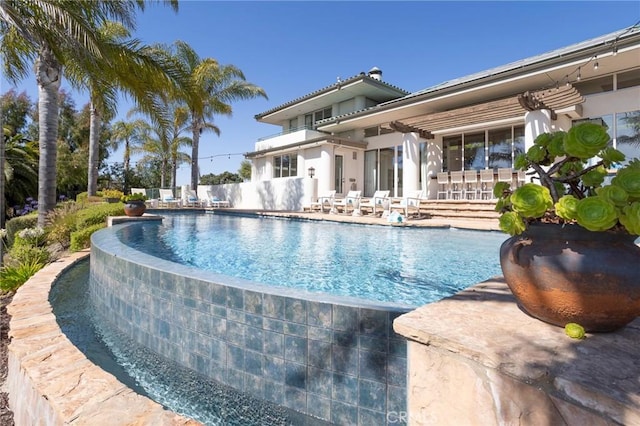 view of pool with an infinity pool and a patio area