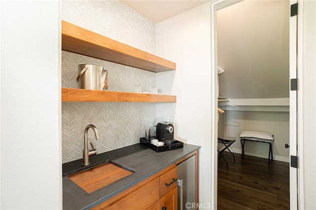 bar featuring dark wood-type flooring, backsplash, a sink, and wine cooler