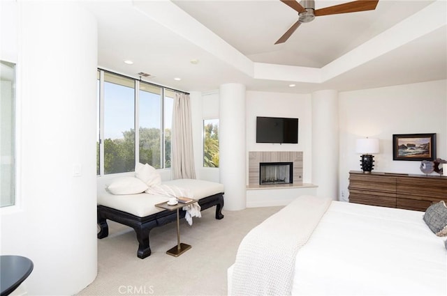 carpeted bedroom with recessed lighting, a raised ceiling, visible vents, a fireplace with raised hearth, and a ceiling fan