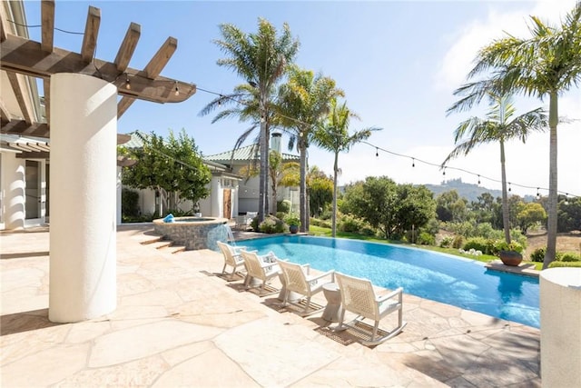 view of pool featuring a pool with connected hot tub, a patio, and a pergola