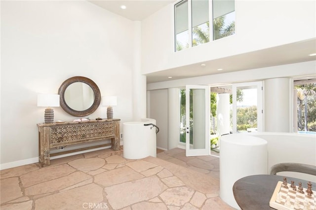 bathroom featuring a towering ceiling, baseboards, and recessed lighting