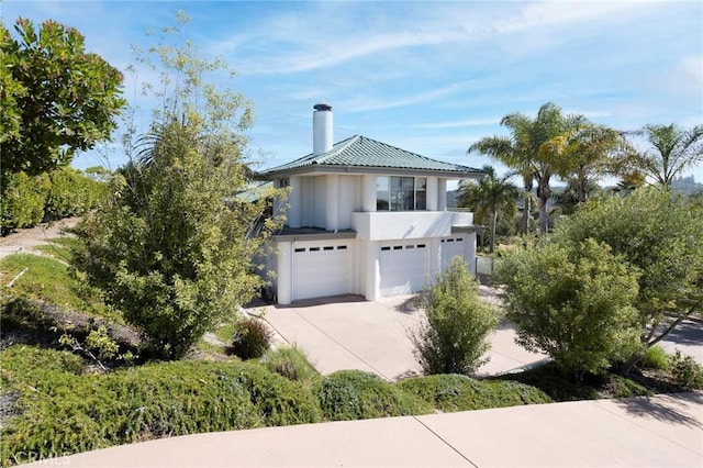 view of front of home with a garage, concrete driveway, a chimney, and stucco siding