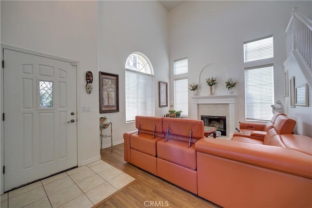 living room with a high ceiling, a fireplace, and light wood-type flooring