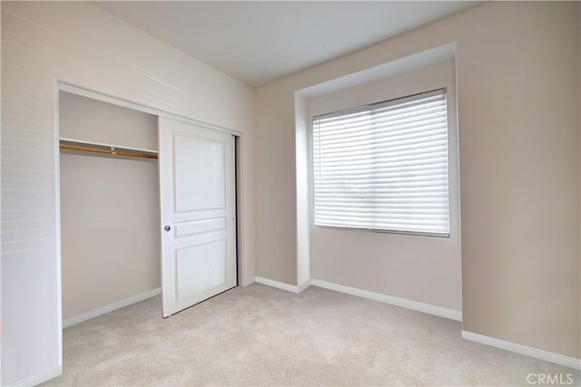 unfurnished bedroom with light colored carpet and a closet