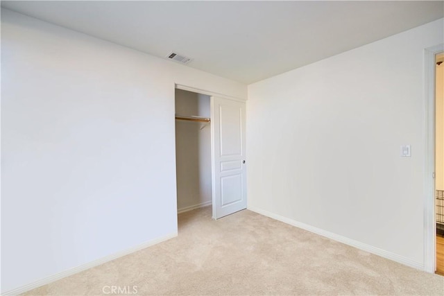 unfurnished bedroom with light colored carpet and a closet