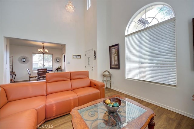 living room with an inviting chandelier, hardwood / wood-style floors, and a high ceiling