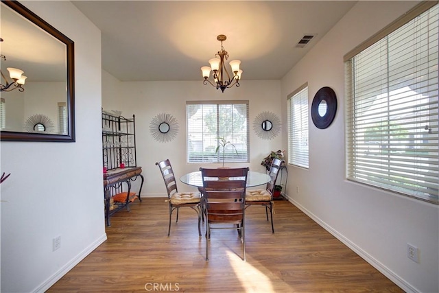 dining area with wood-type flooring and a notable chandelier