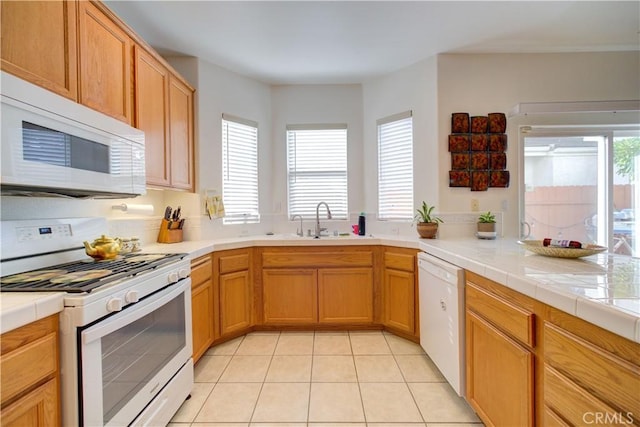 kitchen with sink, a wealth of natural light, white appliances, and light tile patterned floors