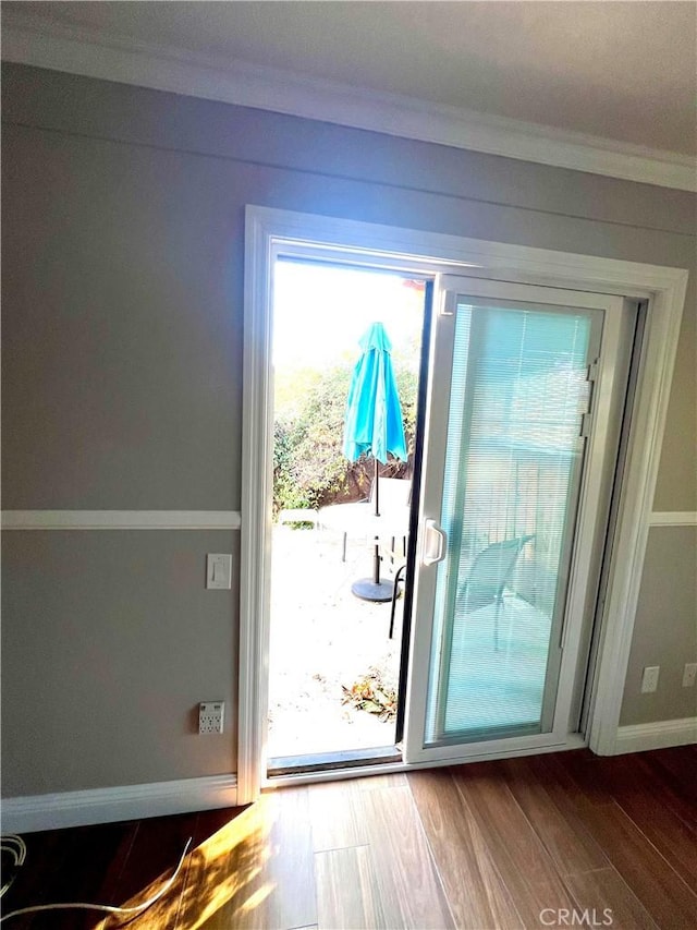 doorway with wood-type flooring and ornamental molding