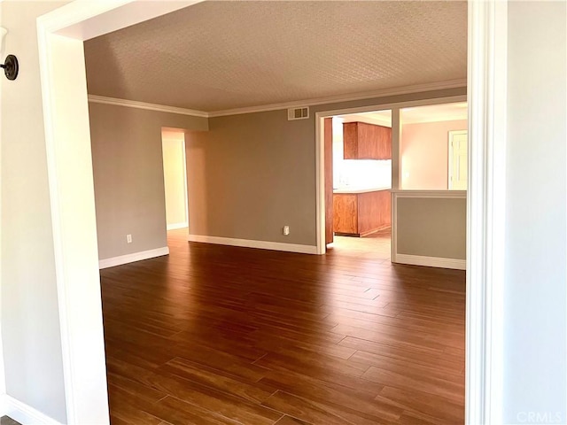 empty room featuring a textured ceiling, ornamental molding, and dark wood-type flooring