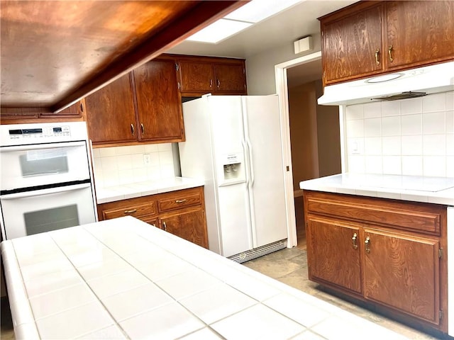 kitchen with tile counters, white appliances, and tasteful backsplash