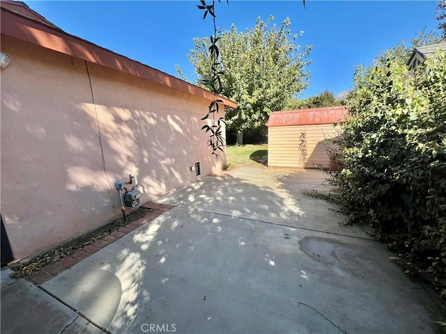 view of side of property with a patio area and a storage unit