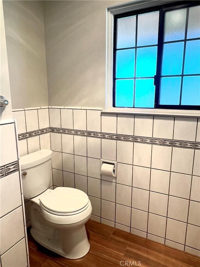 bathroom featuring hardwood / wood-style flooring, tile walls, and toilet