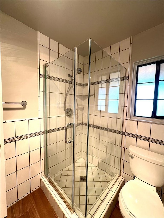 bathroom featuring walk in shower, toilet, and tile walls