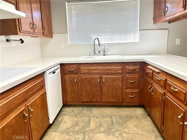 kitchen with backsplash, tile counters, dishwasher, and sink