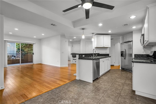 kitchen featuring appliances with stainless steel finishes, sink, hanging light fixtures, hardwood / wood-style floors, and white cabinets