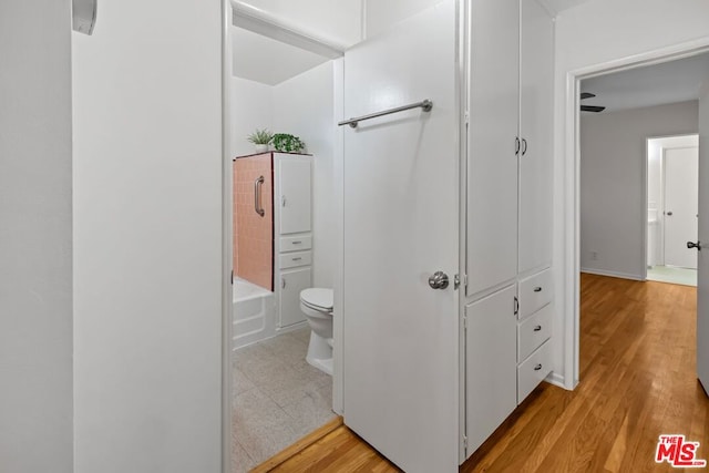 bathroom featuring hardwood / wood-style flooring, ceiling fan, toilet, and bathing tub / shower combination