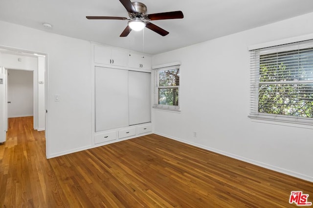 unfurnished bedroom featuring hardwood / wood-style flooring, multiple windows, and ceiling fan