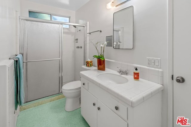 bathroom featuring vanity, toilet, and a shower with door