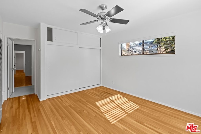 unfurnished bedroom featuring hardwood / wood-style floors, ceiling fan, and a closet