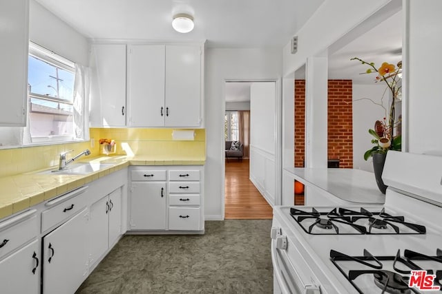 kitchen with hardwood / wood-style floors, white cabinets, tile counters, sink, and white gas stove