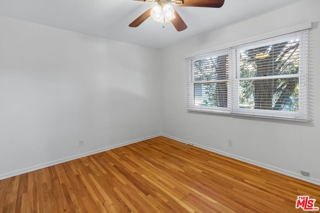 empty room with hardwood / wood-style floors, ceiling fan, and a healthy amount of sunlight