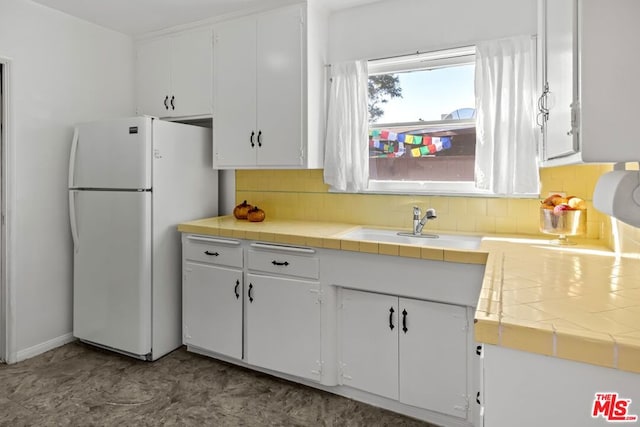 kitchen featuring white cabinets, tile countertops, tasteful backsplash, and white fridge