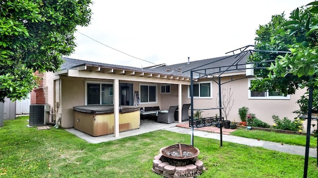 rear view of house featuring a hot tub, central AC, a patio, a lawn, and a fire pit