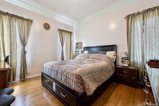 bedroom with light wood-type flooring, multiple windows, and ornamental molding