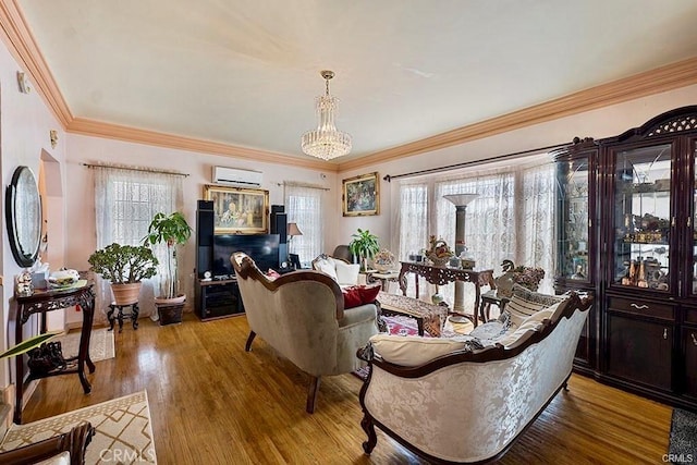 living area with a wall mounted air conditioner, wood-type flooring, crown molding, and a chandelier